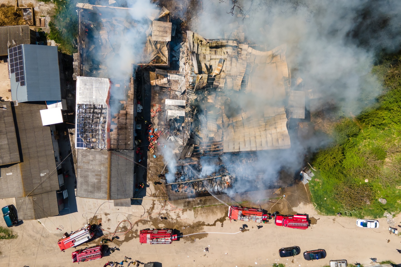 Aerial view of firefighters extinguishing ruined building on fire with collapsed roof and rising